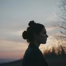 a woman looking out into the distance at sunset