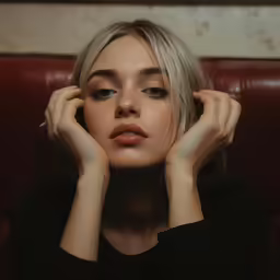 a woman in black shirt holding her hands near her face