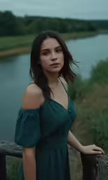 a beautiful woman standing on the fence next to a river