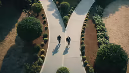 two people in suits walking through a park
