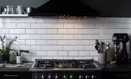 black stove and kitchen appliances in white tiled backsplash