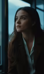 a woman staring out the window while wearing a coat