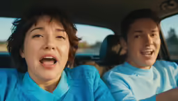 an excited woman and man in the passenger seat of a car