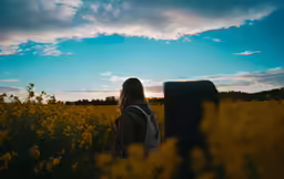 the girl is standing in the field of yellow flowers