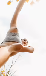 a woman standing in the air holding onto a leaf