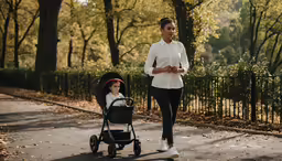 a young woman is jogging with a stroller and baby in the back