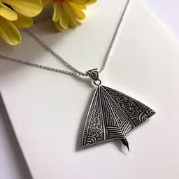 a close up of a silver necklace with a paper airplane,silver plated pendant with a bird on it