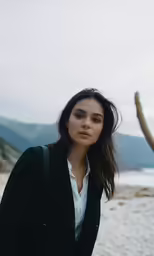 the woman with brown eyes is standing on the beach