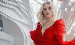a woman in red clothes is standing by a sculpture