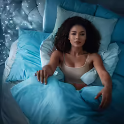 a beautiful woman laying in bed with some pillows