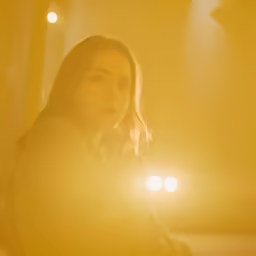 the woman is sitting in the spotlight behind a bright light