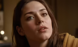 there is a female looking at something while she is wearing a yellow sweater