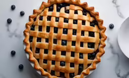 an unbaked pie with blueberries on a table