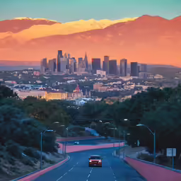 a red car is driving down a street with city skylines behind it