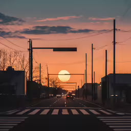cars are driving down the street in front of an orange and yellow sky