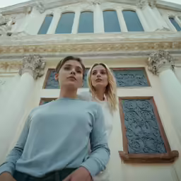 two young women stand in front of a building