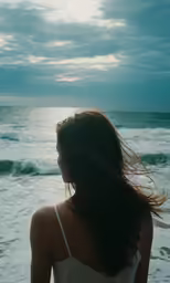 a woman in a tank top is looking at the ocean