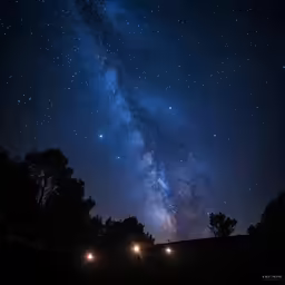 a very bright blue sky filled with stars and lots of trees