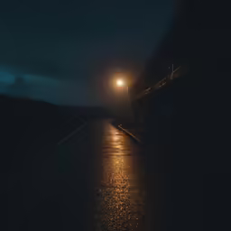 night view of street with light post and light in the distance