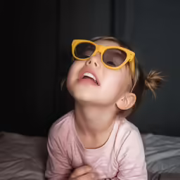 a little girl in yellow sunglasses looking up
