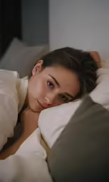 a woman is laying down with her hand on her shoulder