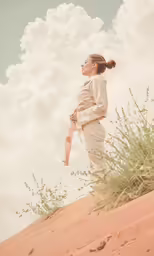 a woman in white clothes is standing on a dune