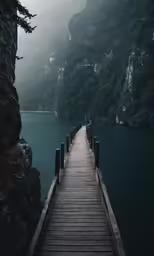 a wooden dock sits in front of some large mountains