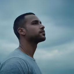 a man standing in front of the sky wearing ear piercings