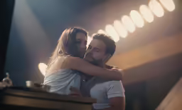 a man and woman hug in a spotlight