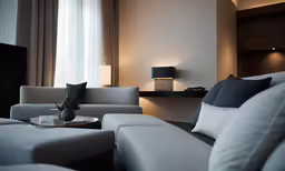 two grey chairs are in the corner of a living room with white furniture