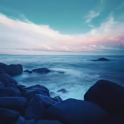 an ocean and rocks under a cloudy sky