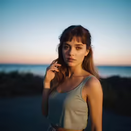 a woman is standing near a beach on a cell phone