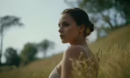 a woman standing on a grass covered hill