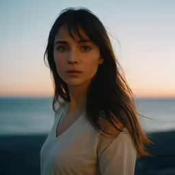 a woman posing for the camera at sunset with her hands behind her back
