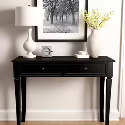 a black table topped with a clock and two white vases