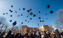 a crowd of students are throwing caps in the air