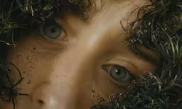 a young boy is covered in freckles and grass