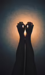 two hands with their fingers are reaching towards a light