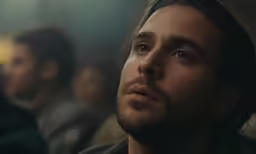 a man stares into the distance as people sit on either side