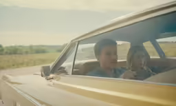 a man and woman sitting in the back seat of a car