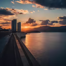 the sun is setting over water by some hills