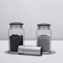 three clear jars one with black and white balls on the lids