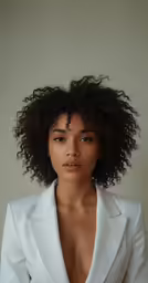 a woman with dark brown hair wearing a white jacket