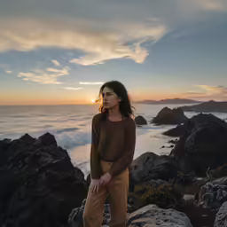 a woman poses for the camera on top of rocks
