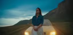 a woman in jeans and a long sleeve shirt standing next to her car