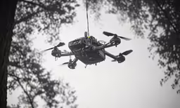 a black propeller air plane flying above some trees