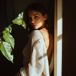 a woman posing for a photo while leaning against the window sill