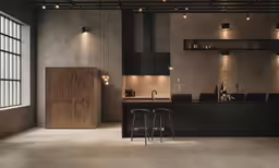 a dimly lit kitchen has two black chairs