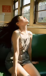 a woman sitting on a green bench in front of a window