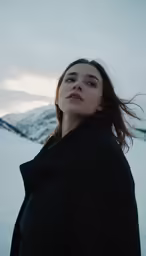 a young woman standing in a field covered in snow